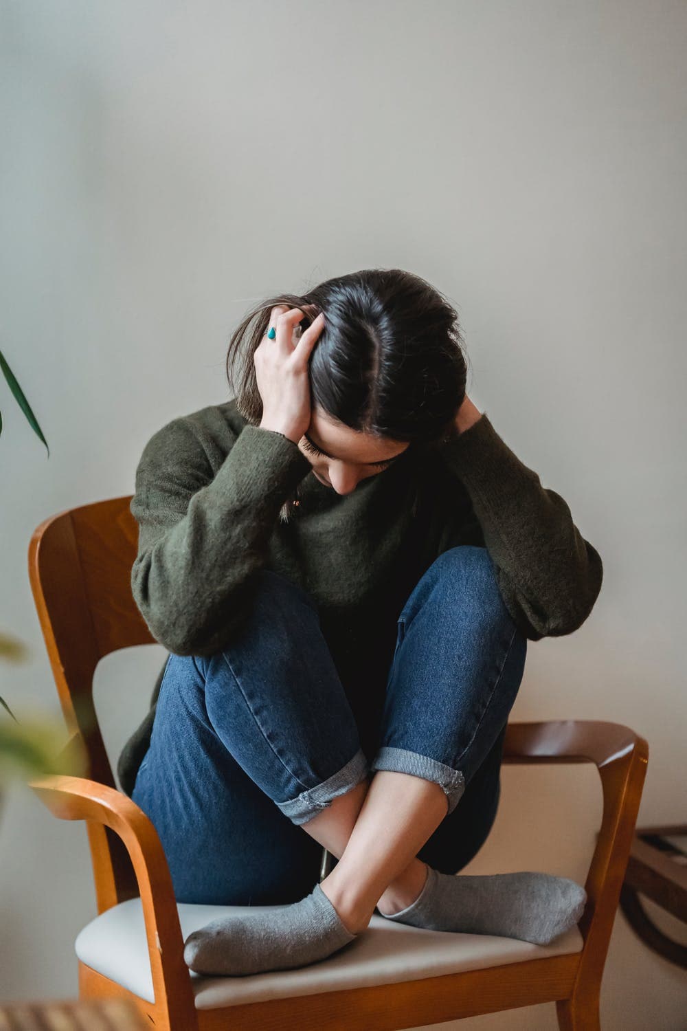 A person sitting quietly in a chair, resting their head in their hands